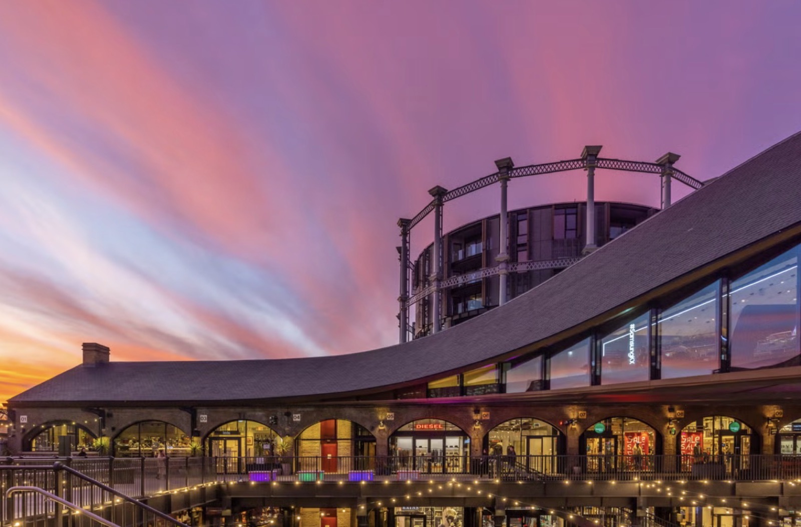 Coal Drops Yard under a pink sunset sky, beside the gasholder buildings
