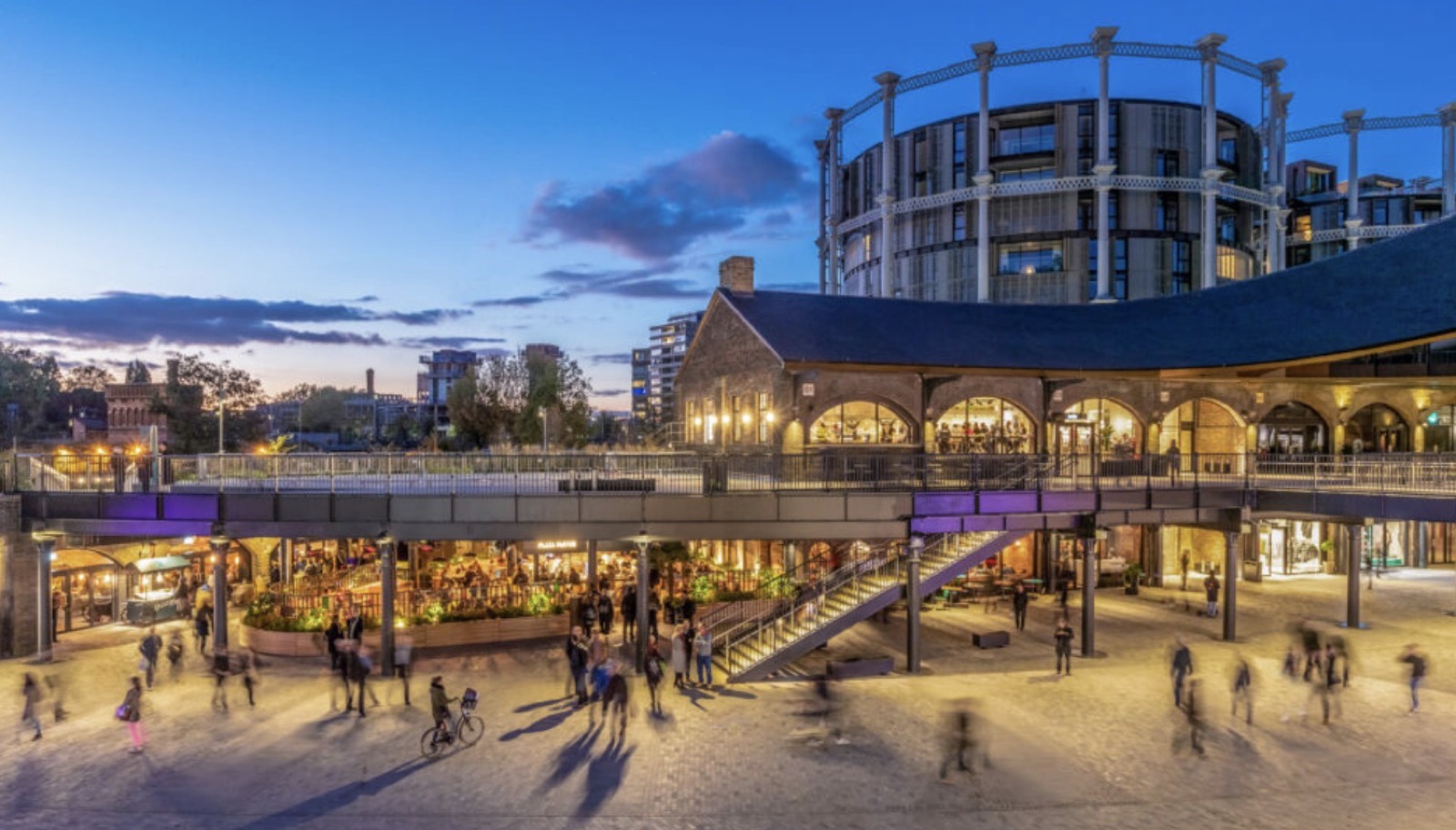 Coal Drops Yard in London at dusk, busy with visitors under the lit-up shops and restaurants