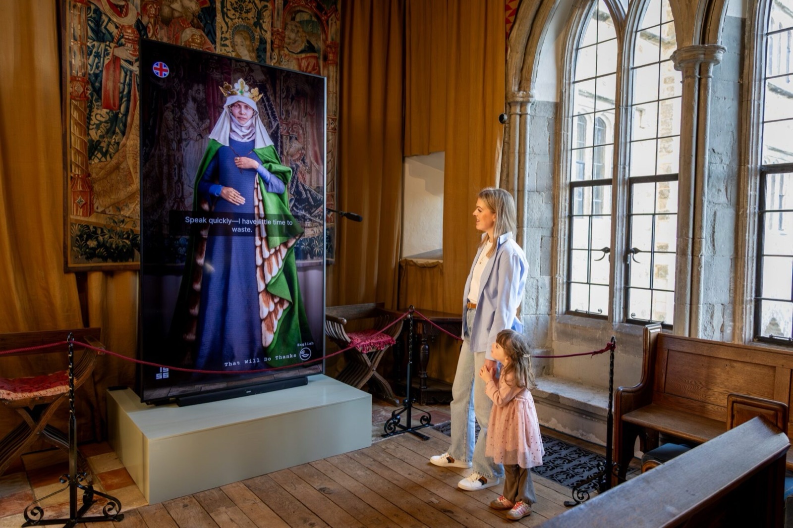A visitor and child in front of the Eleanor of Castile AI avatar at Leeds Castle