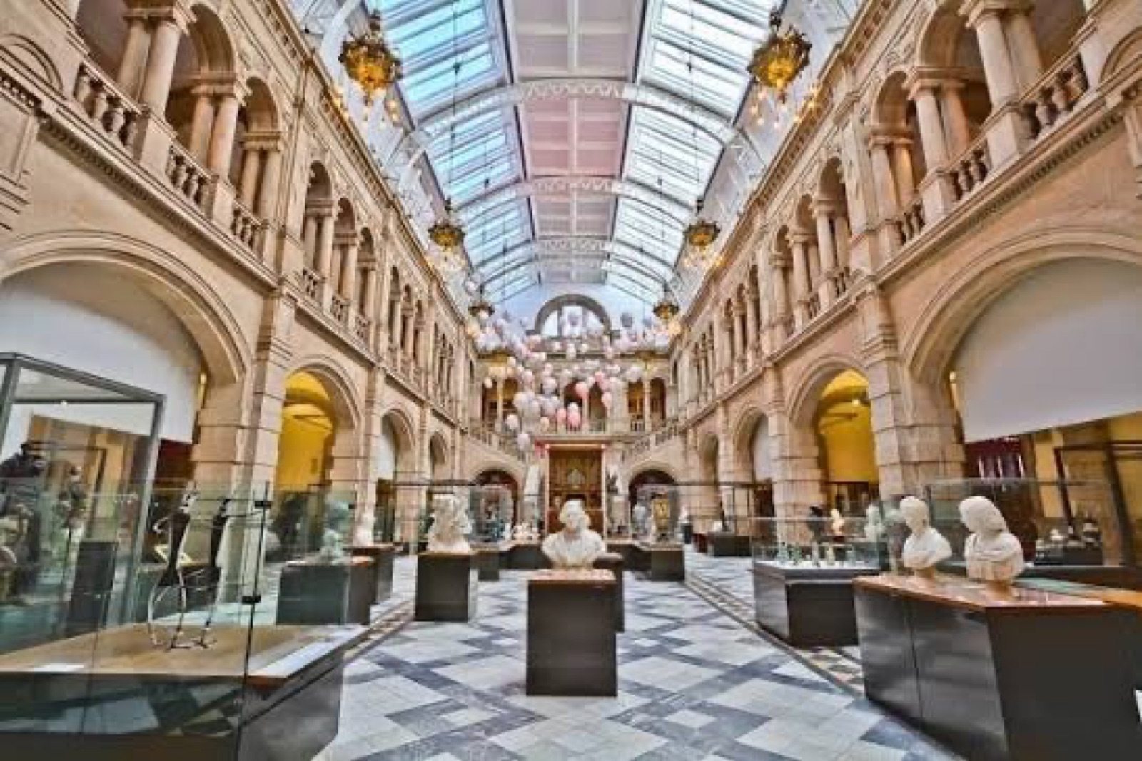 A long museum gallery with a glass roof, sculptures and display cases